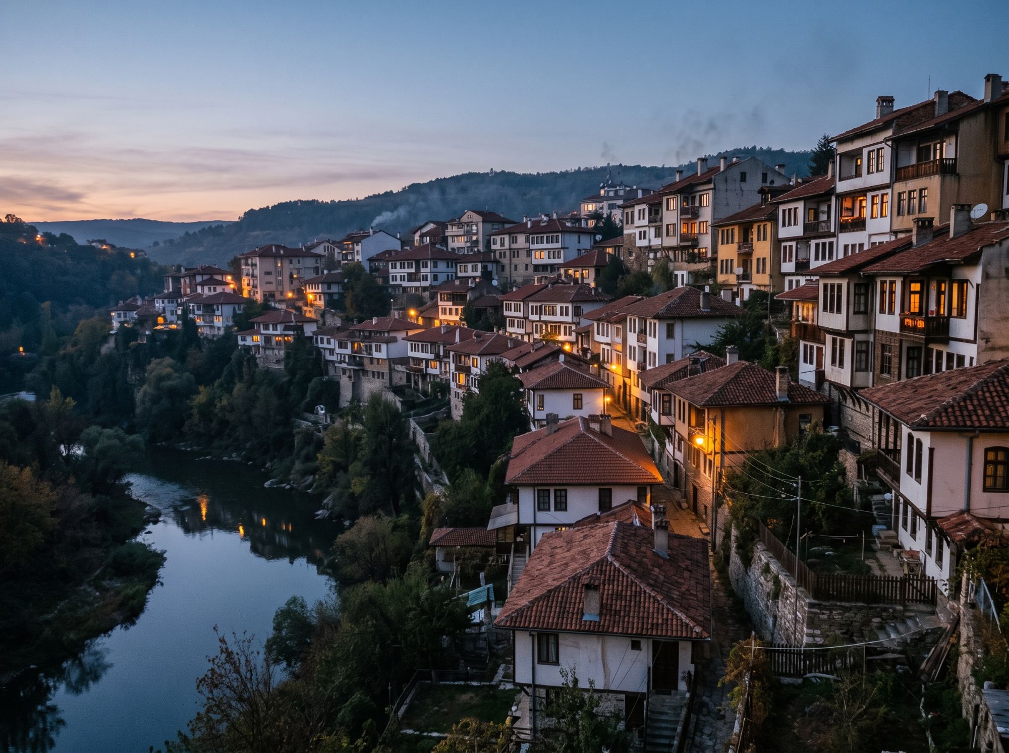 Husene i Veliko Tarnovo i Bulgarien på skrænten over Jantra-floden ved blå time, med lys i vinduerne